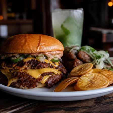 Double smash burger with American cheese, crispy plantain chips and pickled jalapeño on a toasted potato bun — Corunna Street Burger at Two Sisters Kitchen, Flint MI