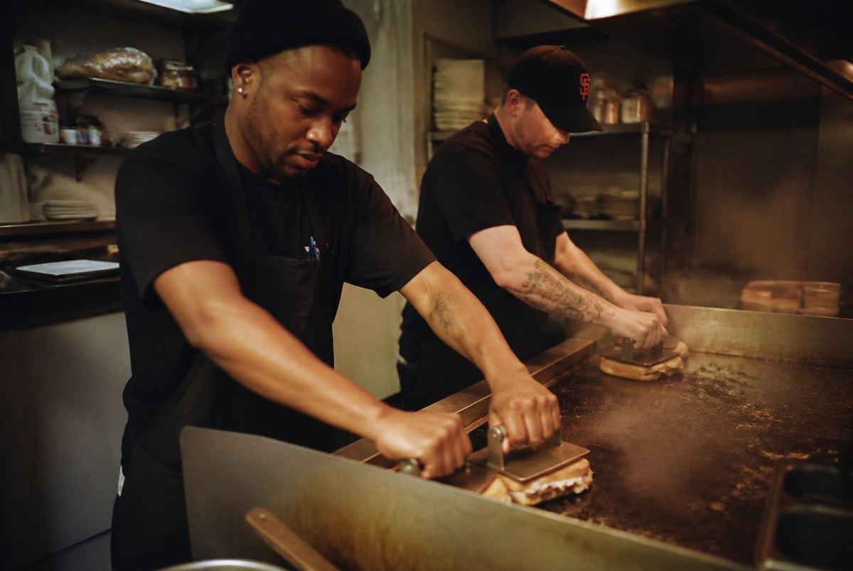 Two Sisters Kitchen cooks pressing sandwiches on the flat top grill in Flint, Michigan